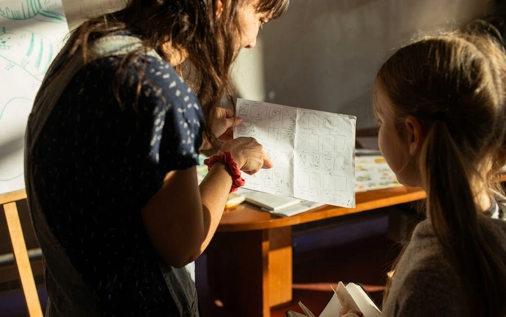 Educadora e criança exploram juntas um livro.
