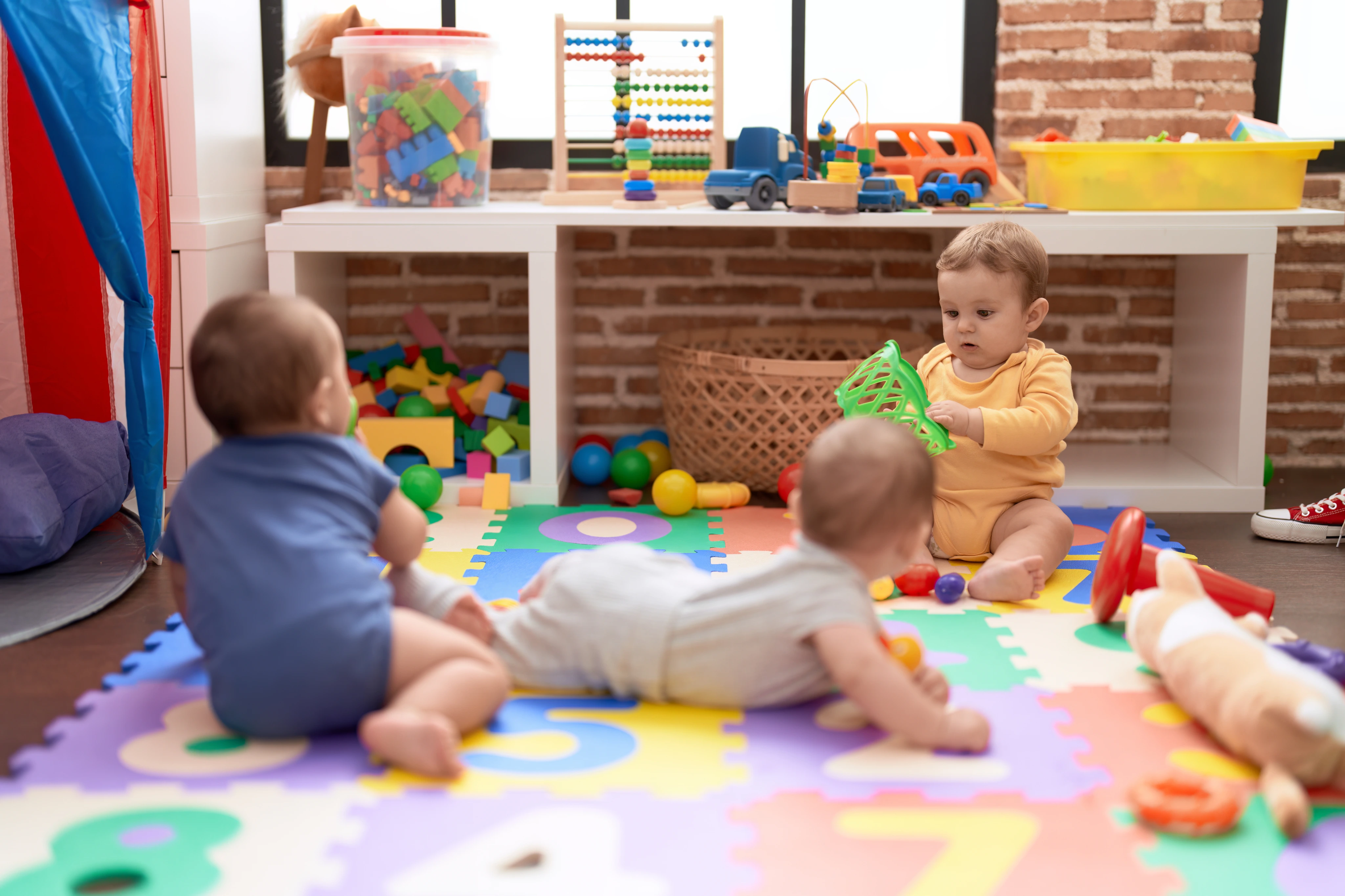 Bebês brincando em um ambiente acolhedor com brinquedos coloridos.
