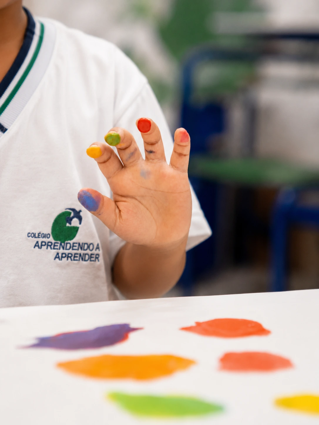 Criança mostra as cores nas mãos em uma atividade de arte.