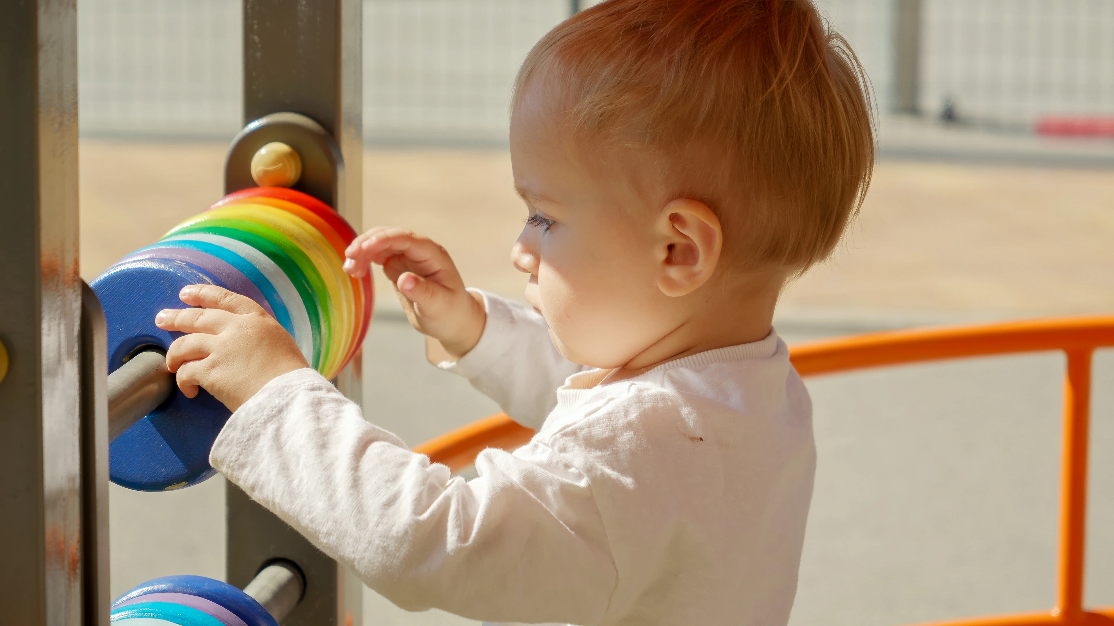 Bebê explora um brinquedo de peças coloridas.